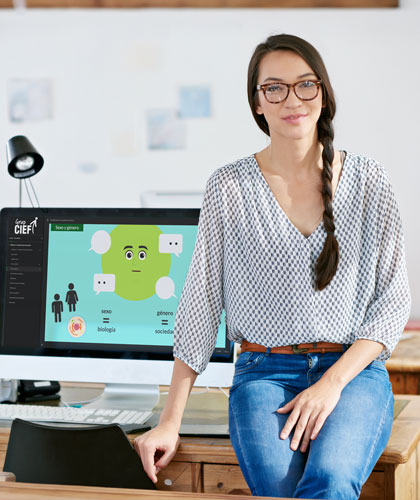 Mujer con gafas sentada en un escritorio junto a un monitor con un curso e-learning de Grup CIEF